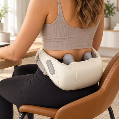 Woman wearing the beige massager around her lower back while seated at a desk