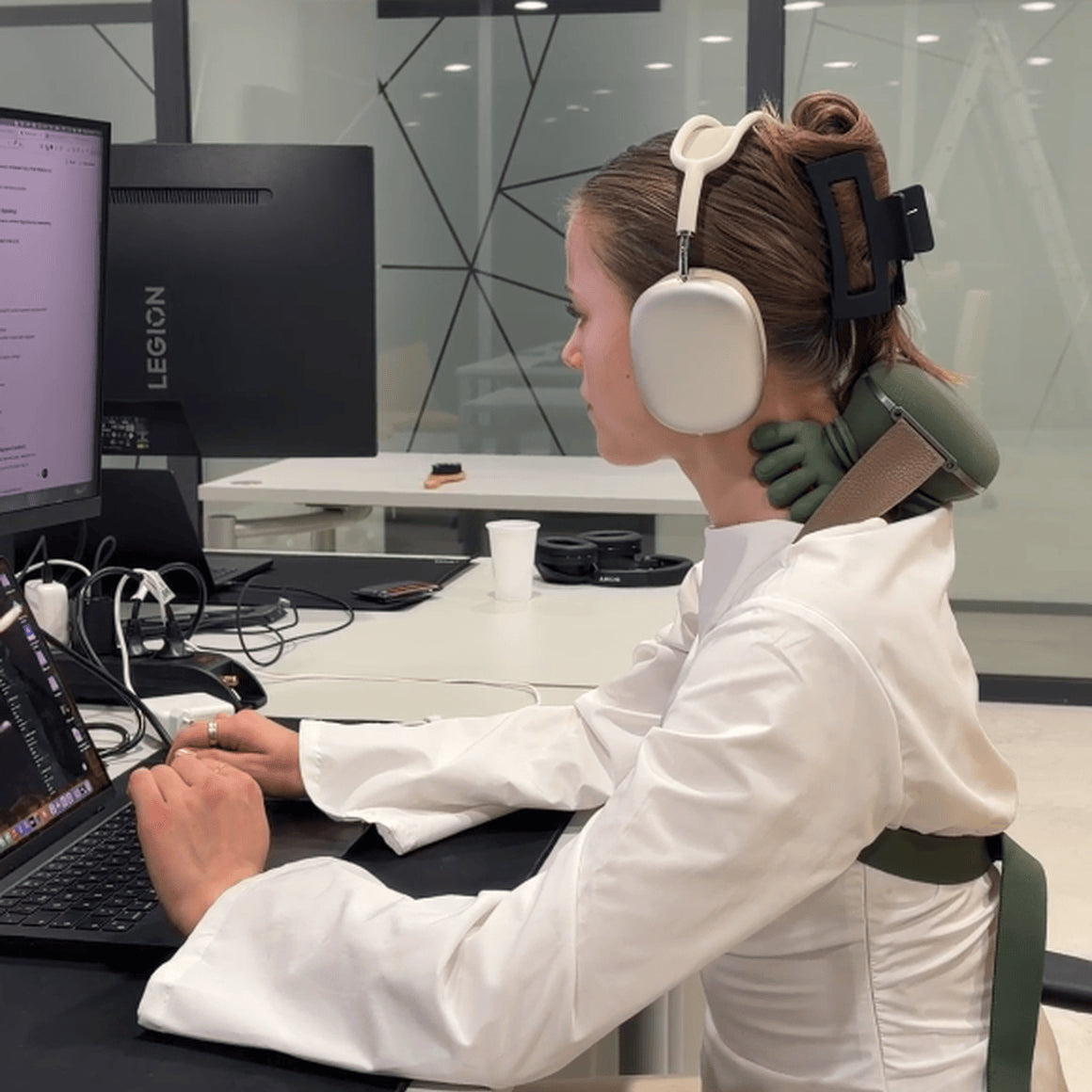 Woman using a green hands-free neck massager while working at a computer