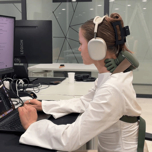 Woman using a green hands-free neck massager while working at a computer