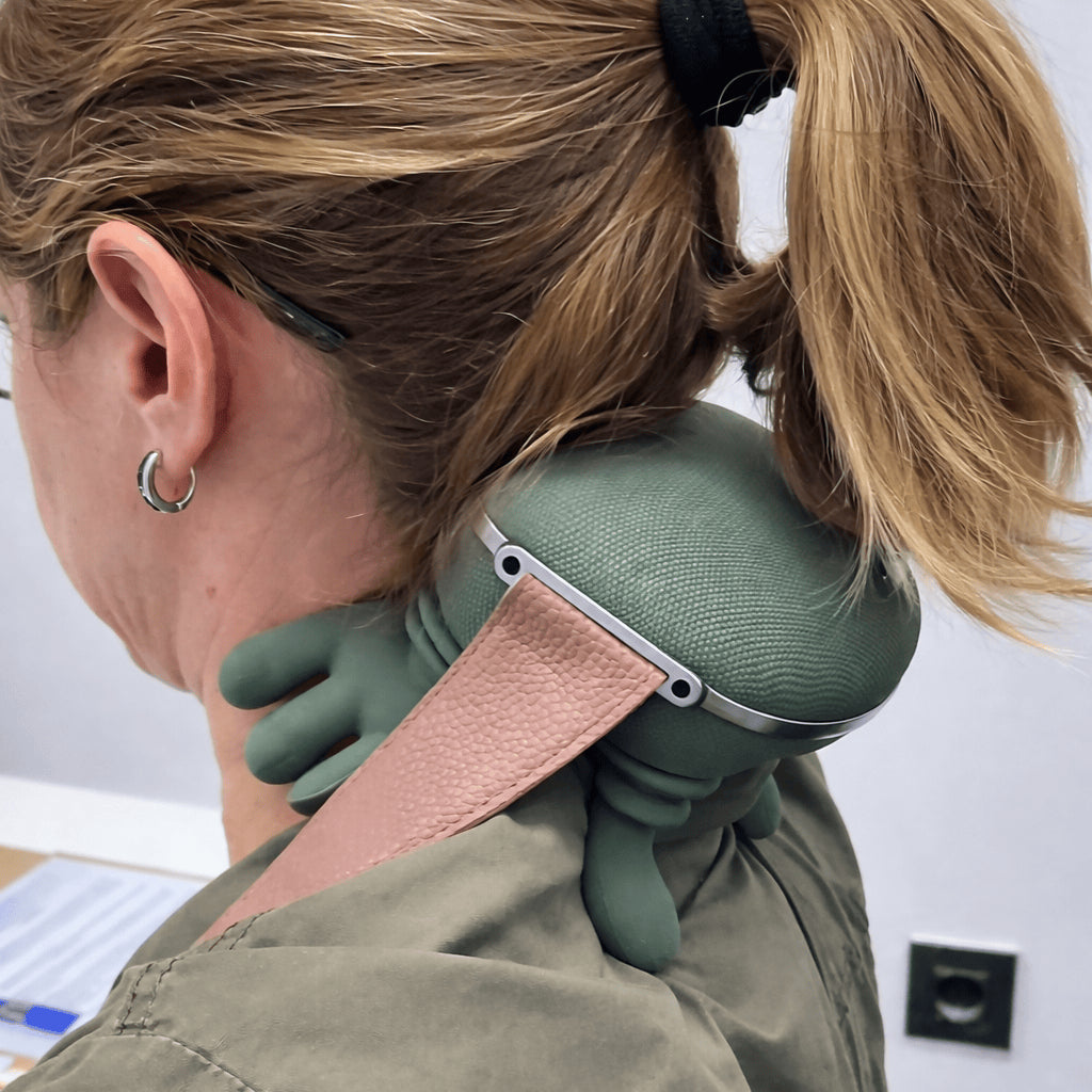 Close-up of a woman wearing the green hands-free massager at the back of her neck