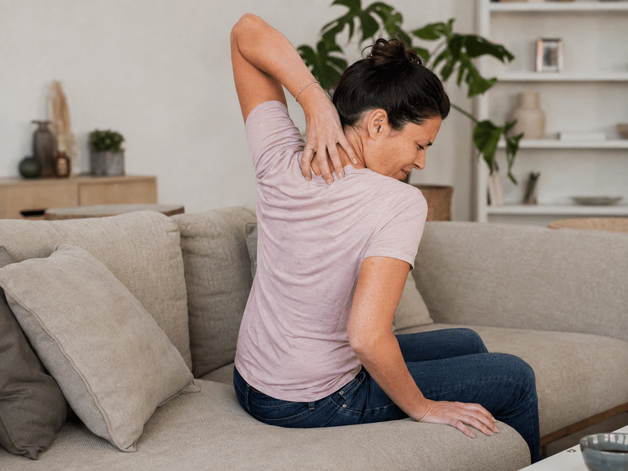 Woman reaching behind her neck while seated indoors